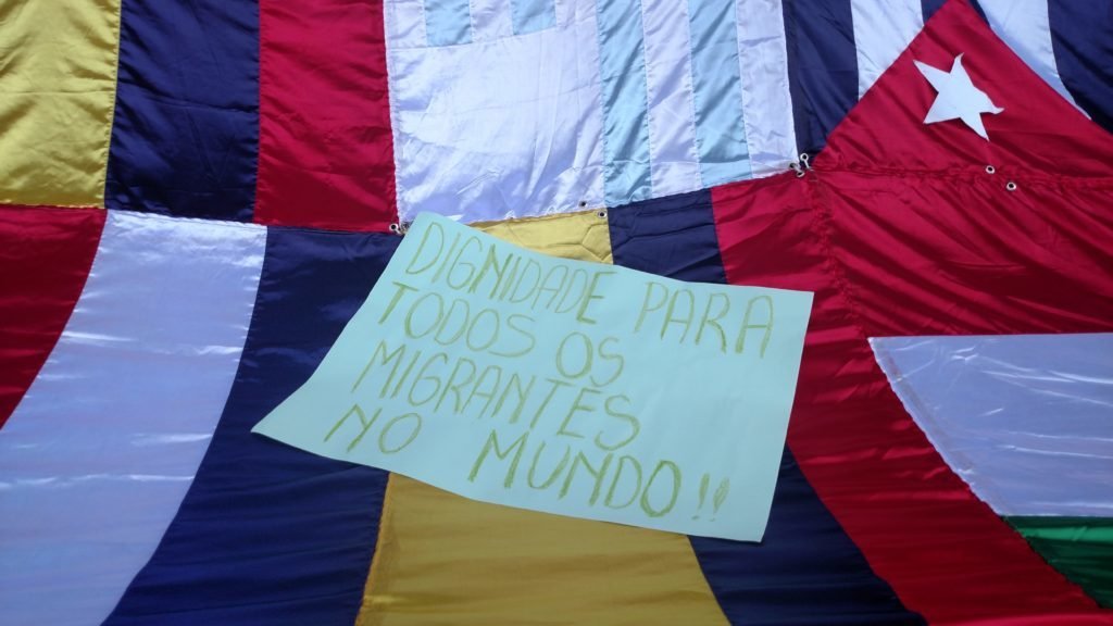 Cartaz na Marcha dos Imigrantes de 2016 pede dignidade para os migrantes no mundo todo. Crédito: Rodrigo Borges Delfim/MigraMundo